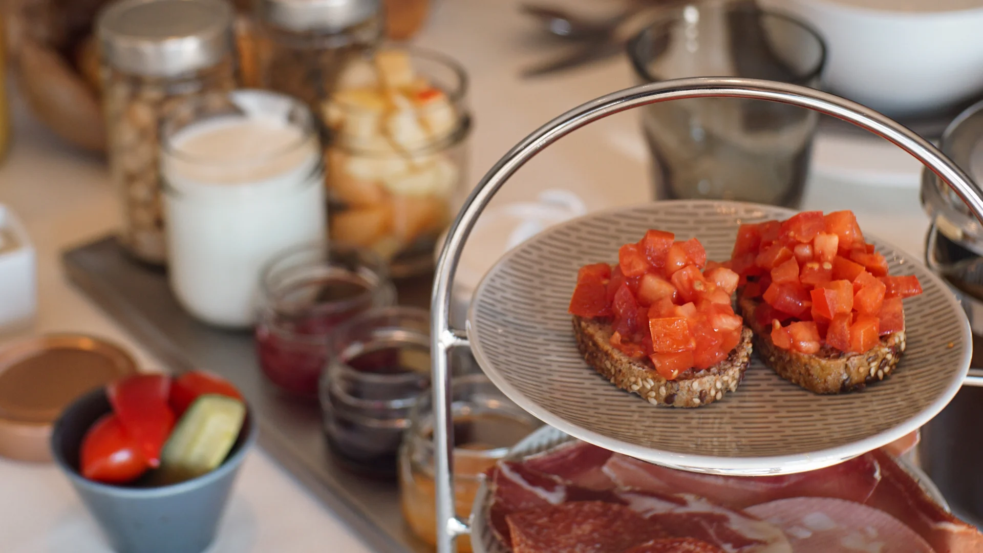 Dreistufiges Tablett mit Bruschetta, Aufschnitt und Käse bei einem Frühstückstisch