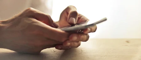 Hand tippt auf Smartphone vor hellem Hintergrund
