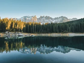 Friedrich ist DAS Boutiquehotel in den Dolomiten Blick auf bewaldete Berge und ihre Spiegelung in einem ruhigen See