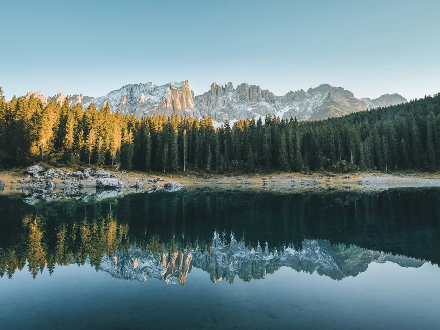 Blick auf bewaldete Berge und ihre Spiegelung in einem ruhigen See