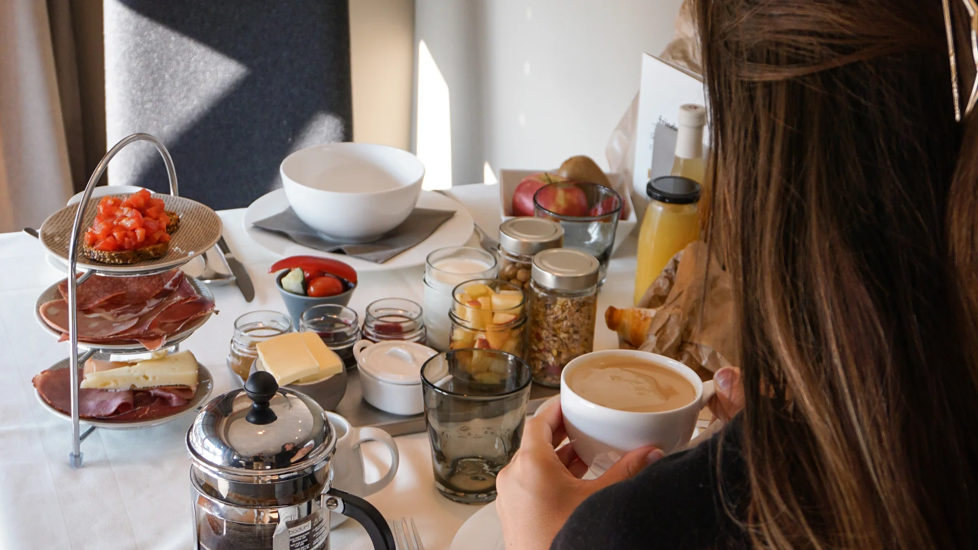 Frau trinkt Kaffee am Tisch mit Frühstück und Küchenutensilien