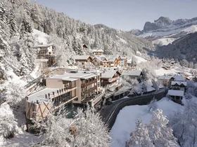 Friedrich ist DAS Boutiquehotel in den Dolomiten Verschneites Bergdorf mit Häusern und Wald in winterlicher Landschaft