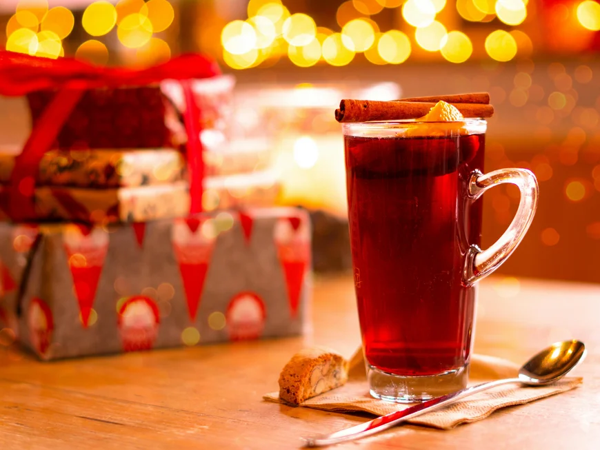 Ihr werdet dieses Skihotel in den Dolomiten lieben. Glühwein mit Zimtstange und Keksen vor weihnachtlichem Hintergrund