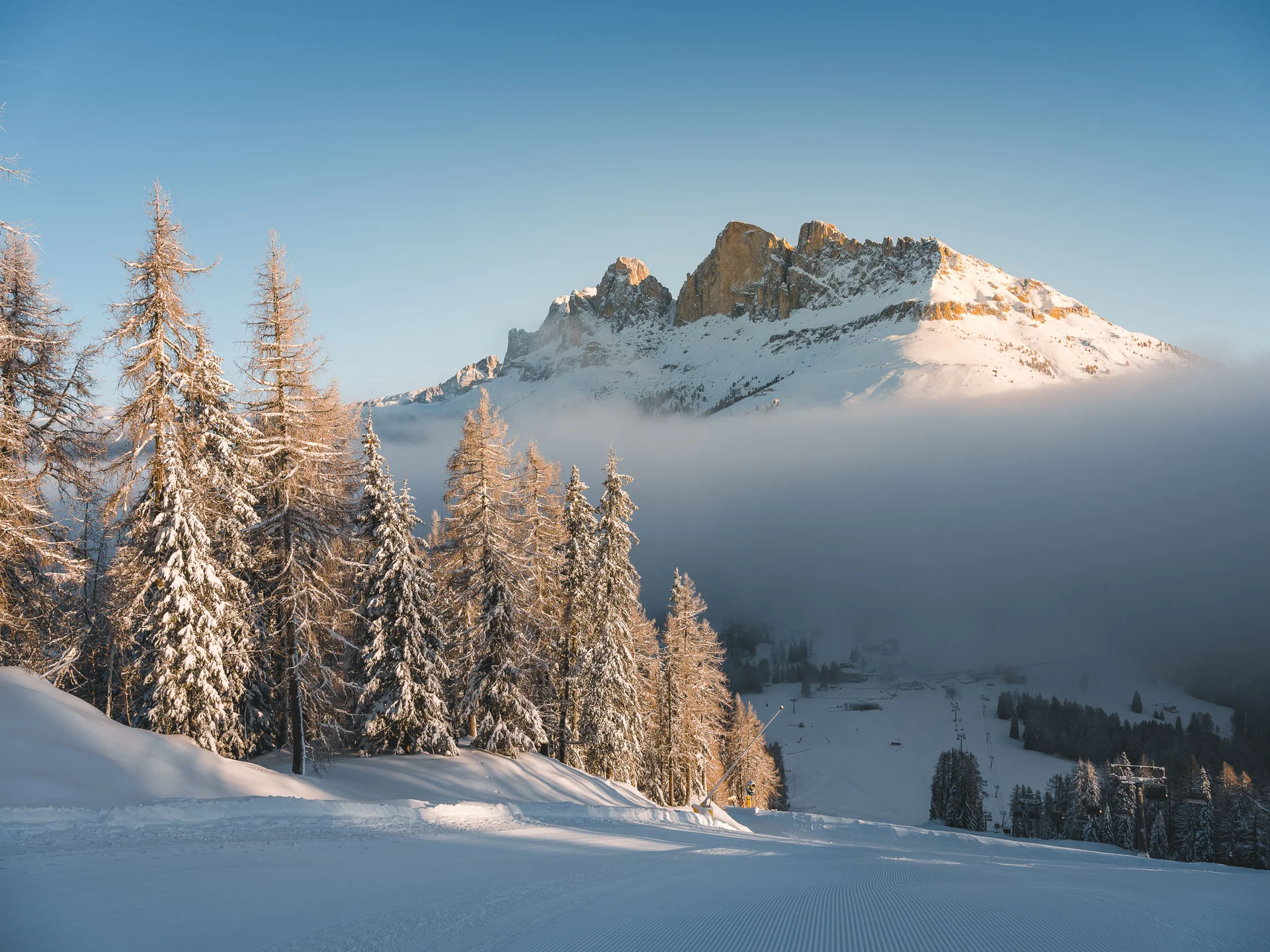 Ihr werdet dieses Skihotel in den Dolomiten lieben. Schneebedeckte Bäume und Berge im Sonnenlicht mit blauem Himmel