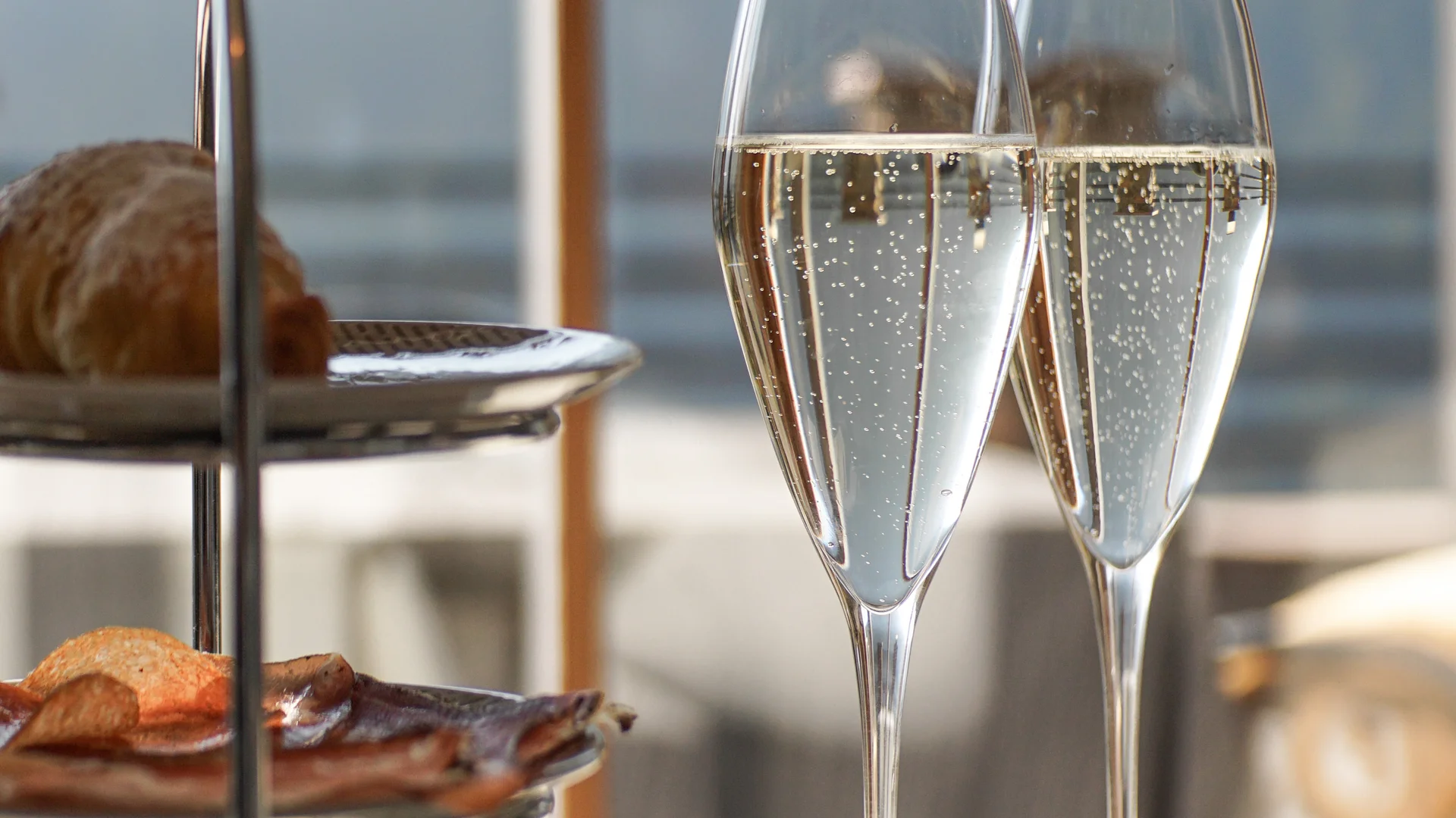 Zwei Gläser Sekt neben einer Etagere mit Gebäck auf einem Tisch