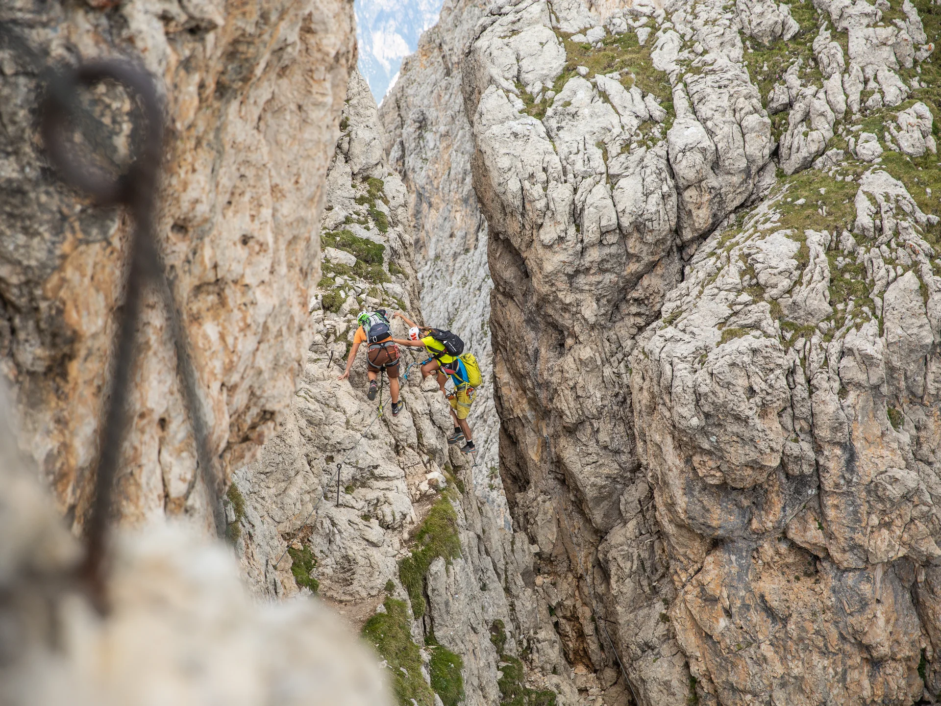 Seid ihr bereit für euren Sommerurlaub in den Dolomiten? Zwei Kletterer erklimmen eine felsige Bergschlucht mit Kletterausrüstung