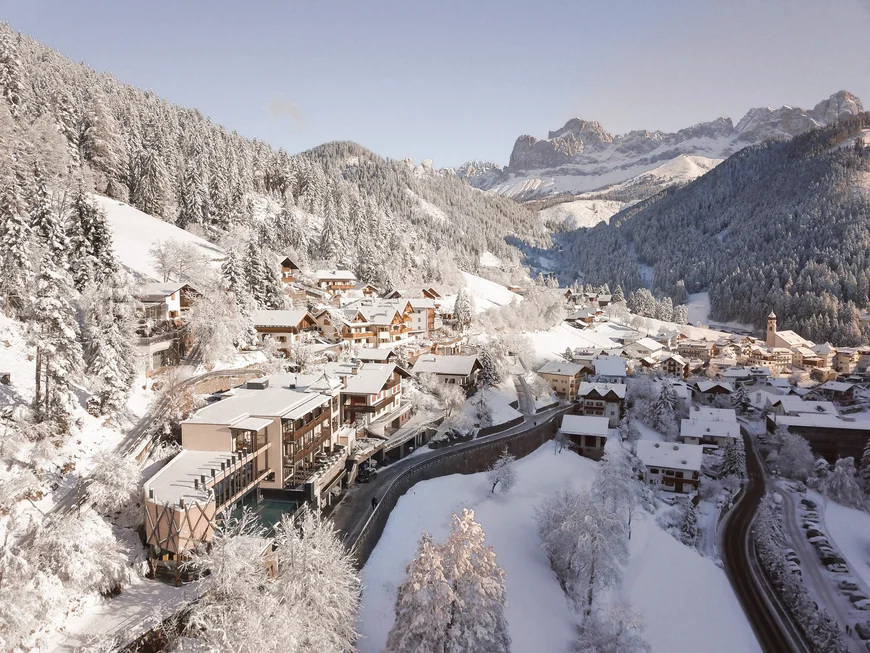 Das ist nicht irgendein nachhaltiges Hotel in Südtirol Winterlandschaft mit schneebedecktem Dorf und Bergen im Hintergrund