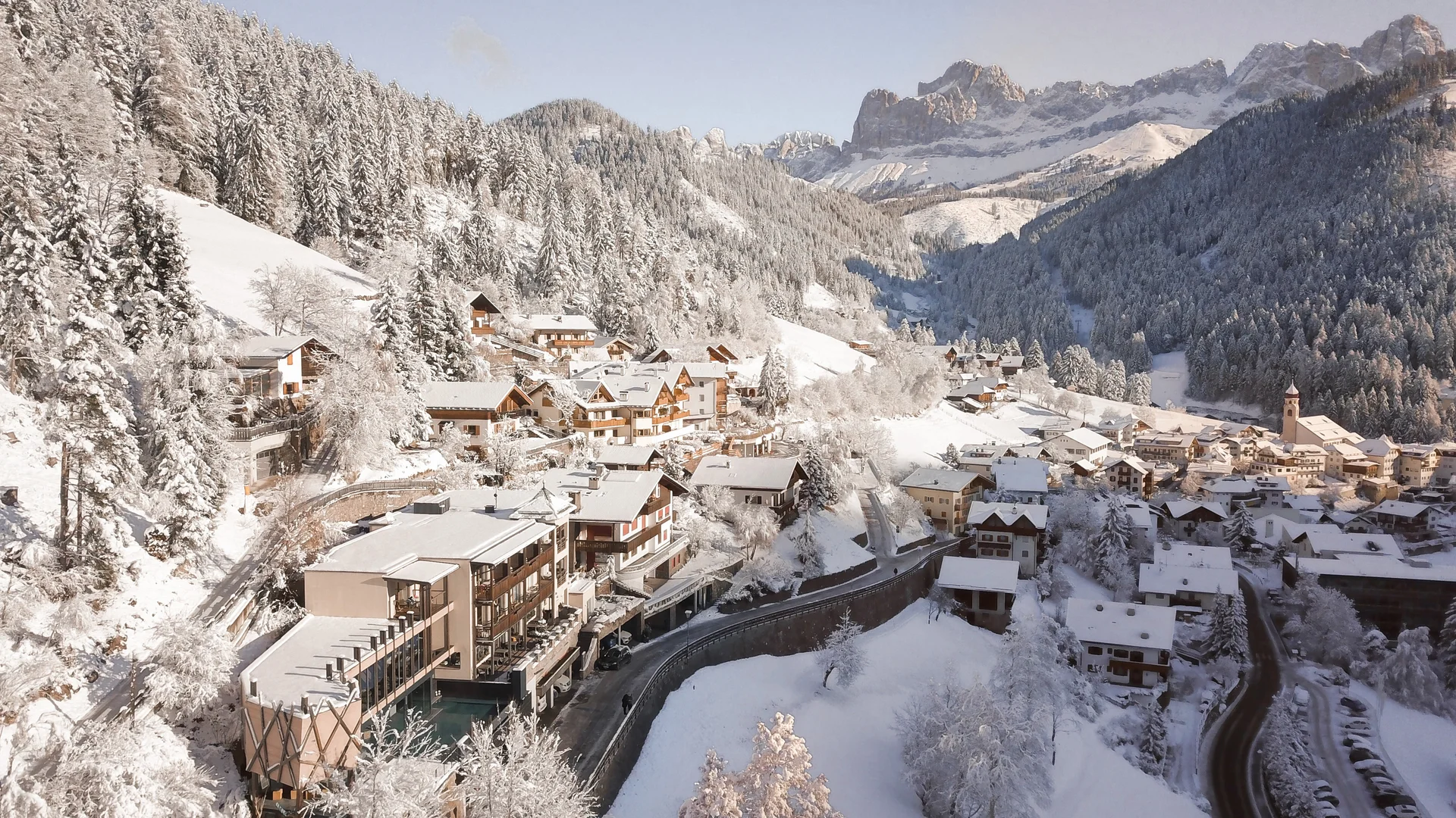 Friedrich ist DAS Boutiquehotel in den Dolomiten Winterlandschaft mit schneebedecktem Dorf und Bergen im Hintergrund