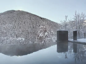 Friedrich ist DAS Boutiquehotel in den Dolomiten Ein Außenpool spiegelt einen schneebedeckten Wald und Berg im Winter