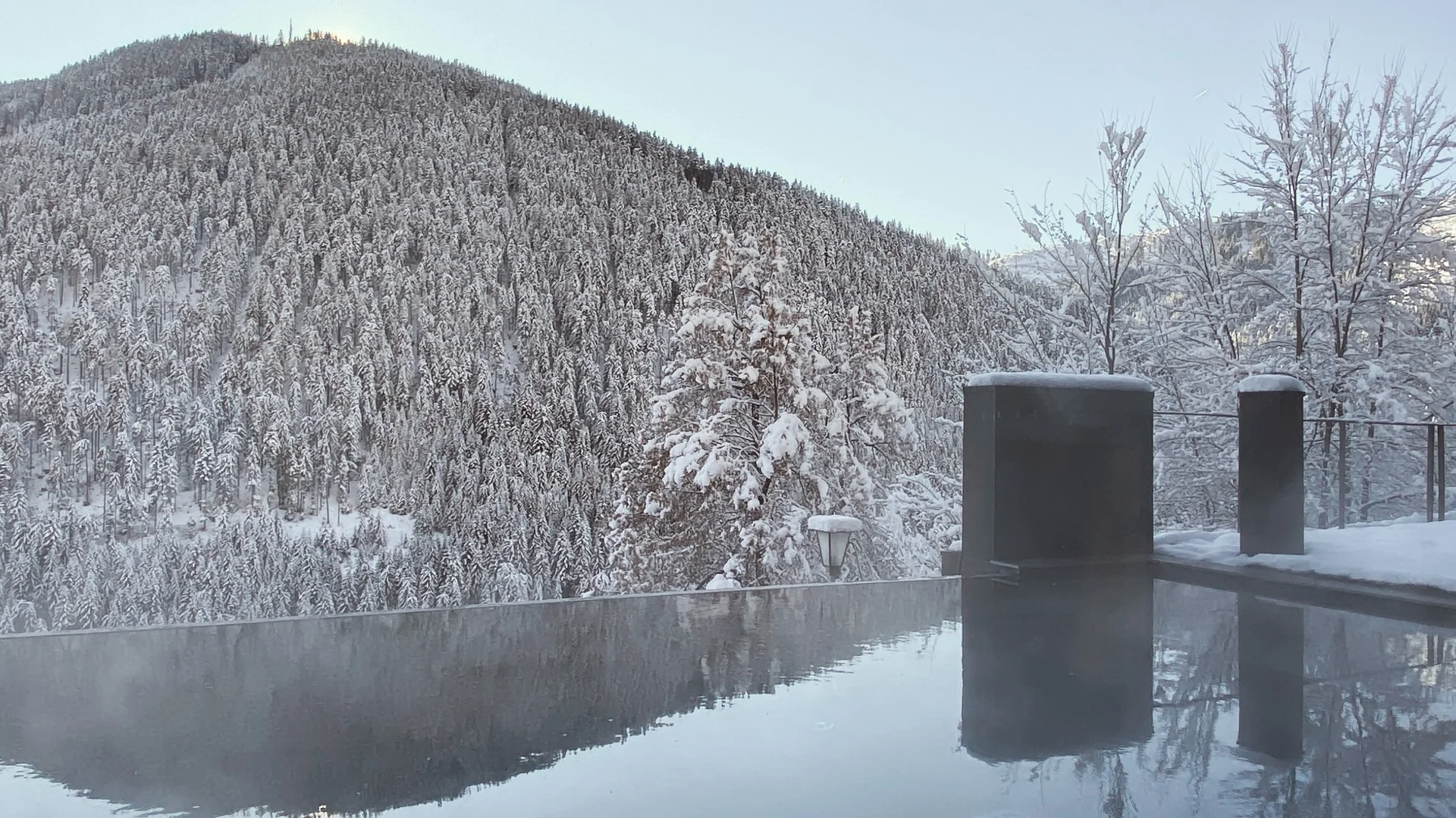 Il Friedrich in foto Una piscina all’aperto riflette un bosco e una montagna innevati in inverno
