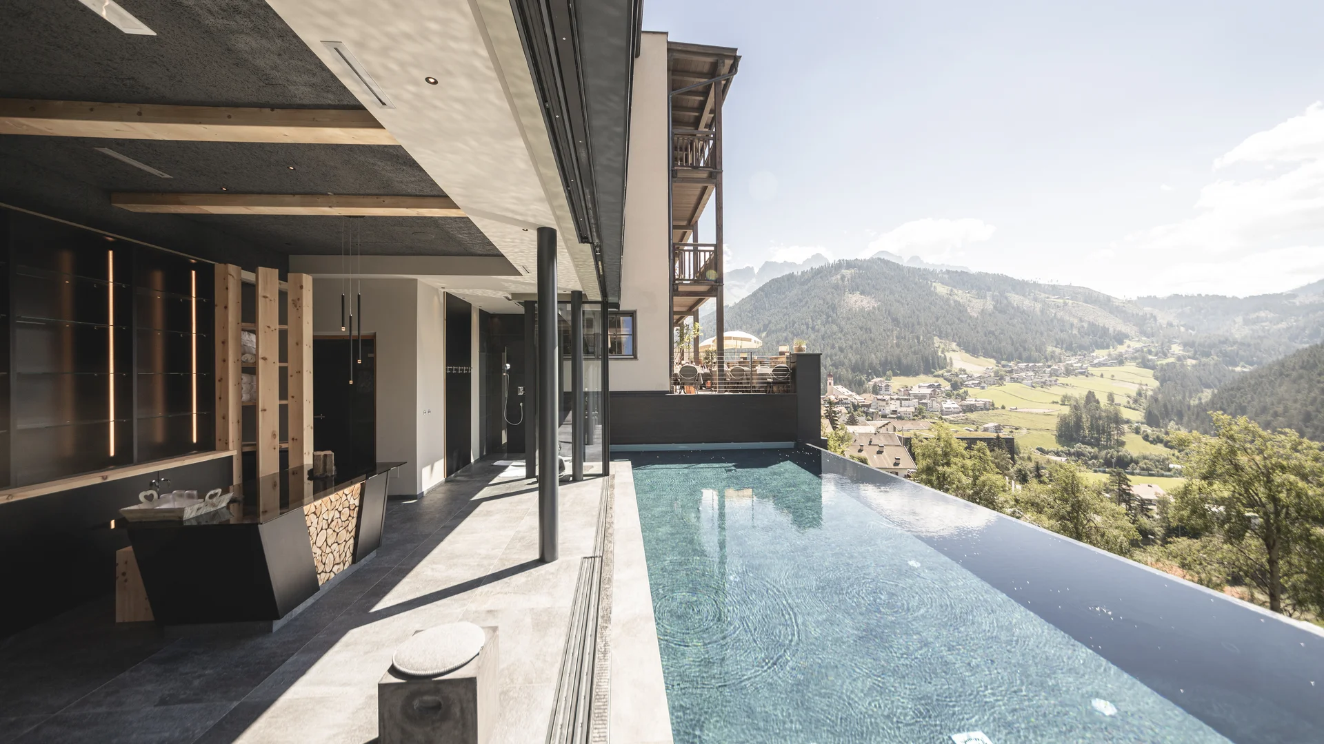 Infinity-Pool mit Bergblick an modernem Hotel in sonniger Landschaft