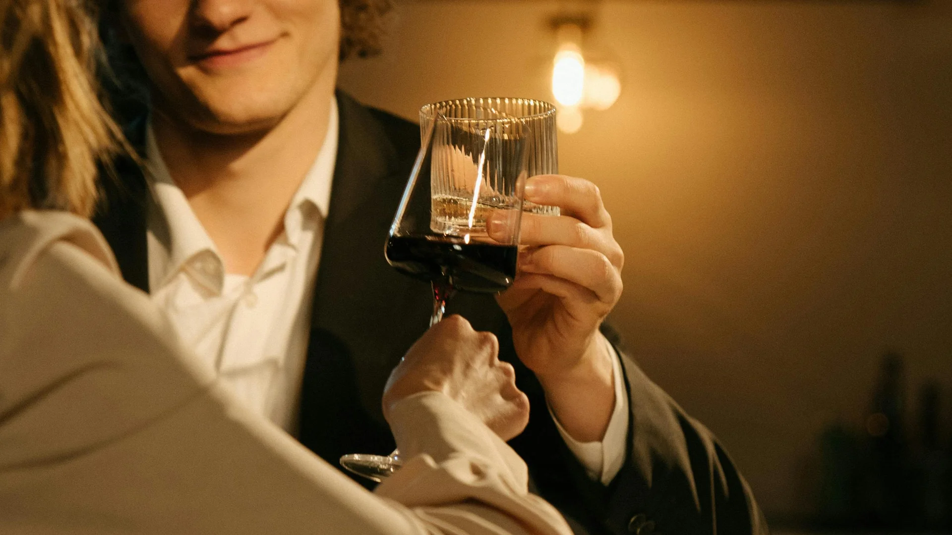 Wein und Bar | Friedrich Welschnofen Zwei Personen stoßen mit Weingläsern in warmer Beleuchtung an