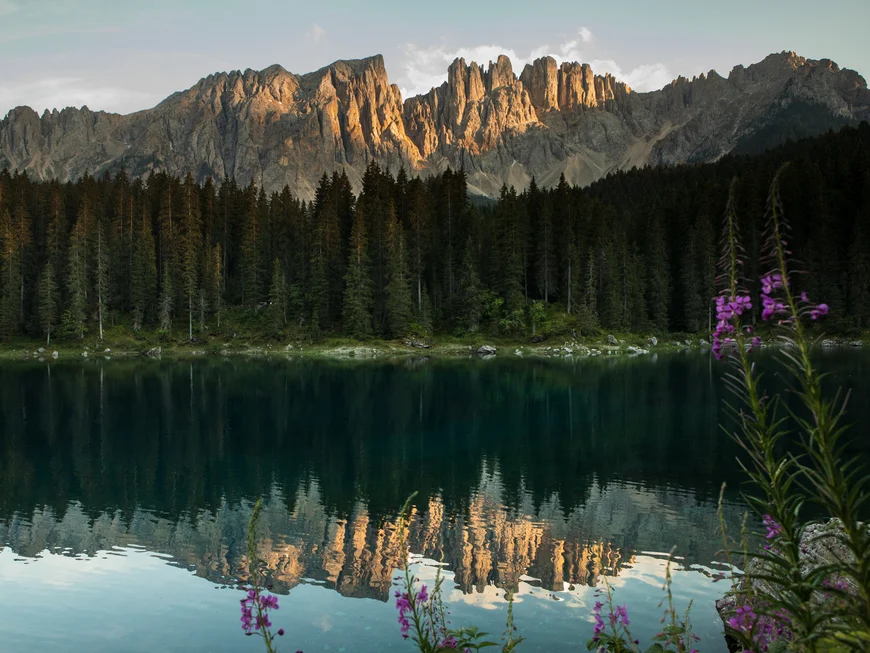 Karersee & Rosengarten Sonnenbeschienene Bergspitzen spiegeln sich in ruhigem See vor dunklem Wald