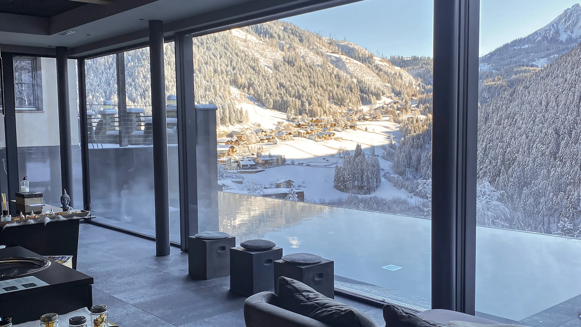 Il vostro hotel con infinity pool sulle Dolomiti Piscina interna con vista su una valle montana innevata, area lounge e piccoli rinfreschi