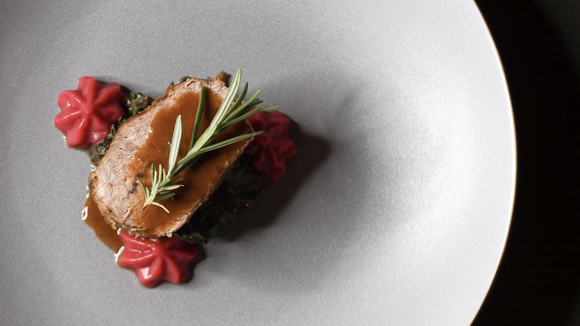 Das ist nicht irgendein nachhaltiges Hotel in Südtirol Elegantes Gericht mit Fleisch, Sauce und Rosmarinzweigen auf weißem Teller