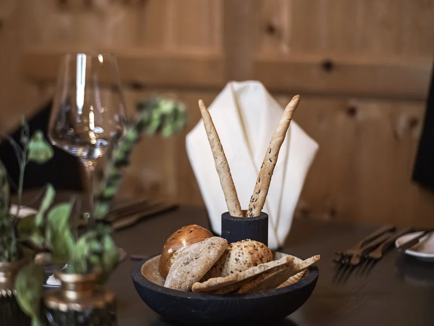 Auf ins Genusshotel nach Südtirol! Verschiedene Brotsorten und Grissini auf einem gedeckten Restauranttisch