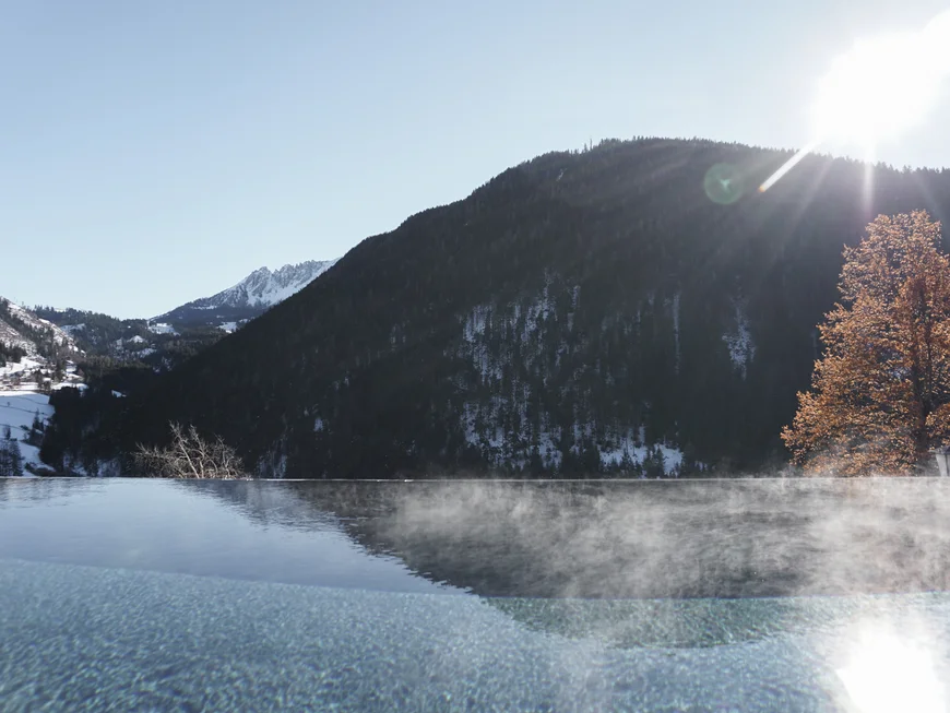 Friedrich ist DAS Boutiquehotel in den Dolomiten Dampfendes beheiztes Pool mit Bergblick im Sonnenschein