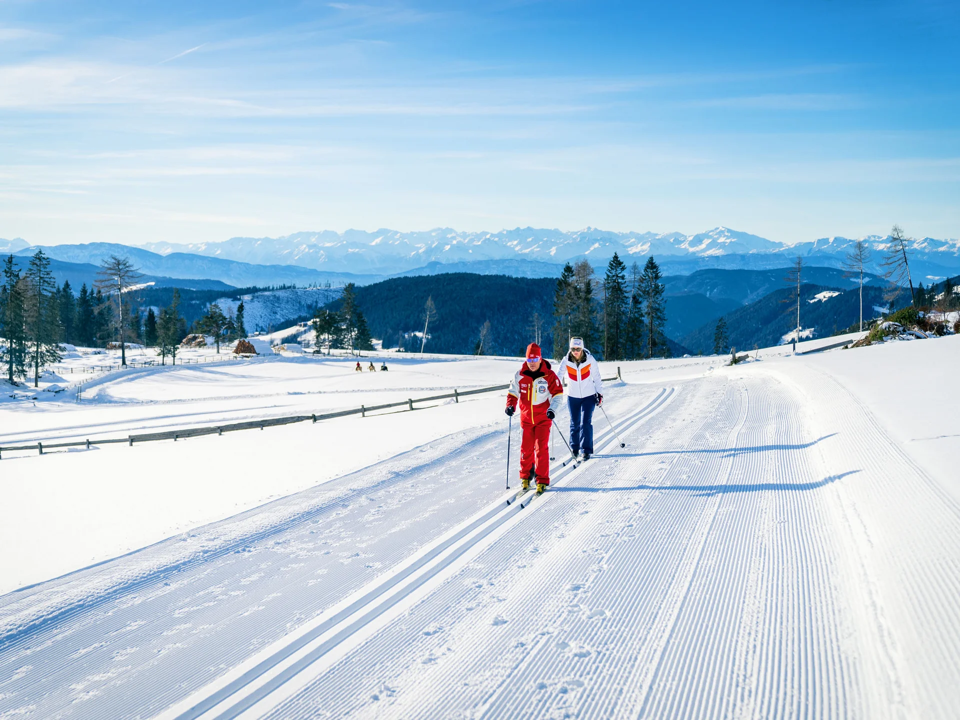 Ihr werdet dieses Skihotel in den Dolomiten lieben. Langläufer auf einer präparierten Schneeloipe mit Bergen im Hintergrund