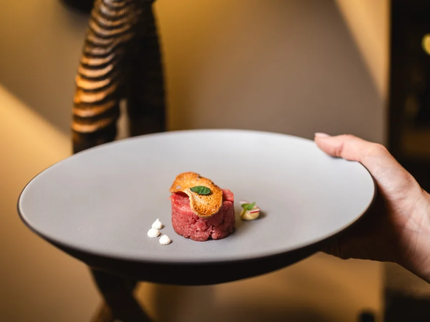 Regionale Küche in Südtirol Hände halten Teller mit serviertem rohem Fleisch und Crostini