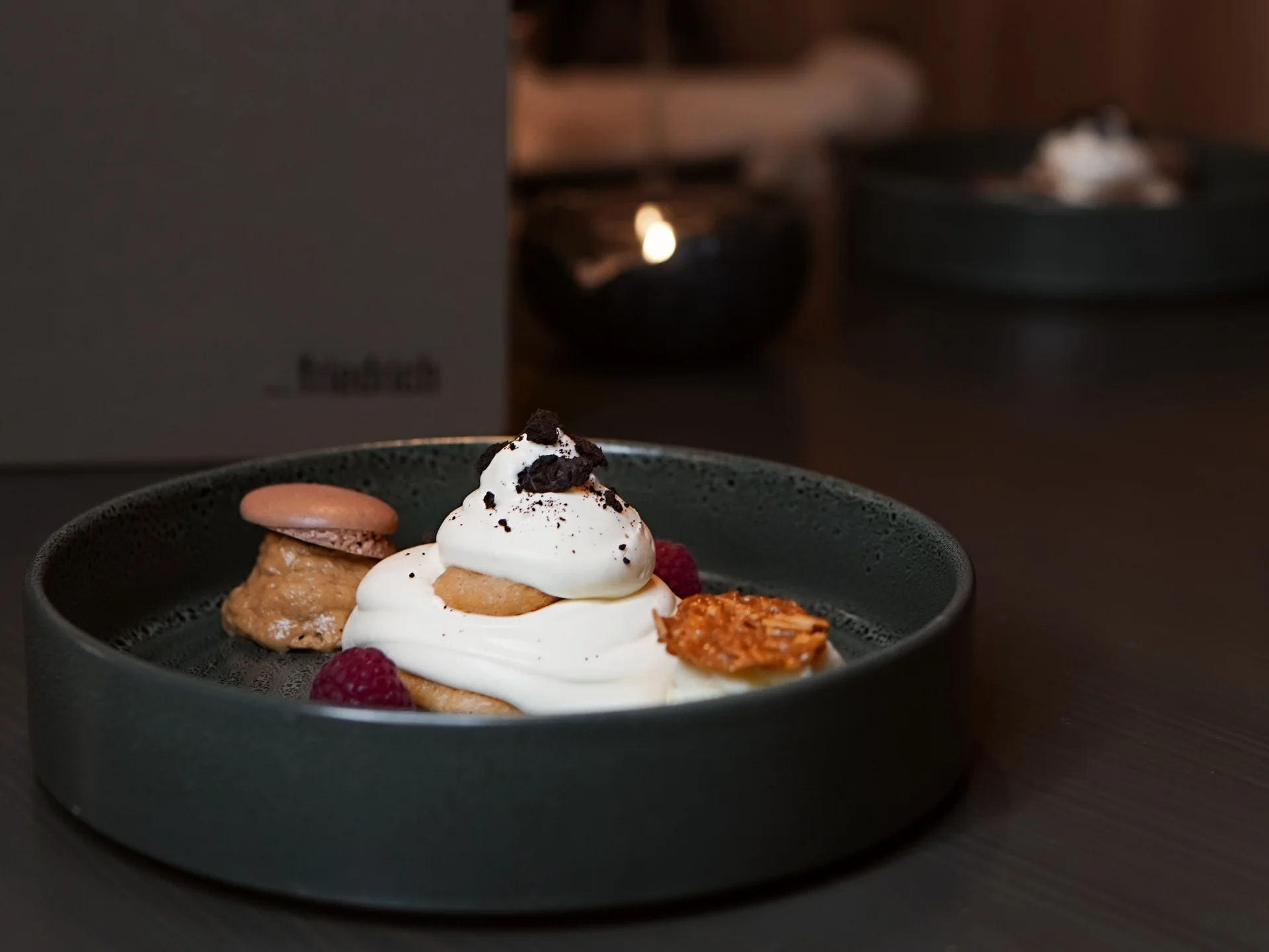 Friedrich ist DAS Boutiquehotel in den Dolomiten Dessert mit Sahne, Keks, Himbeeren und Karamell auf dunklem Teller