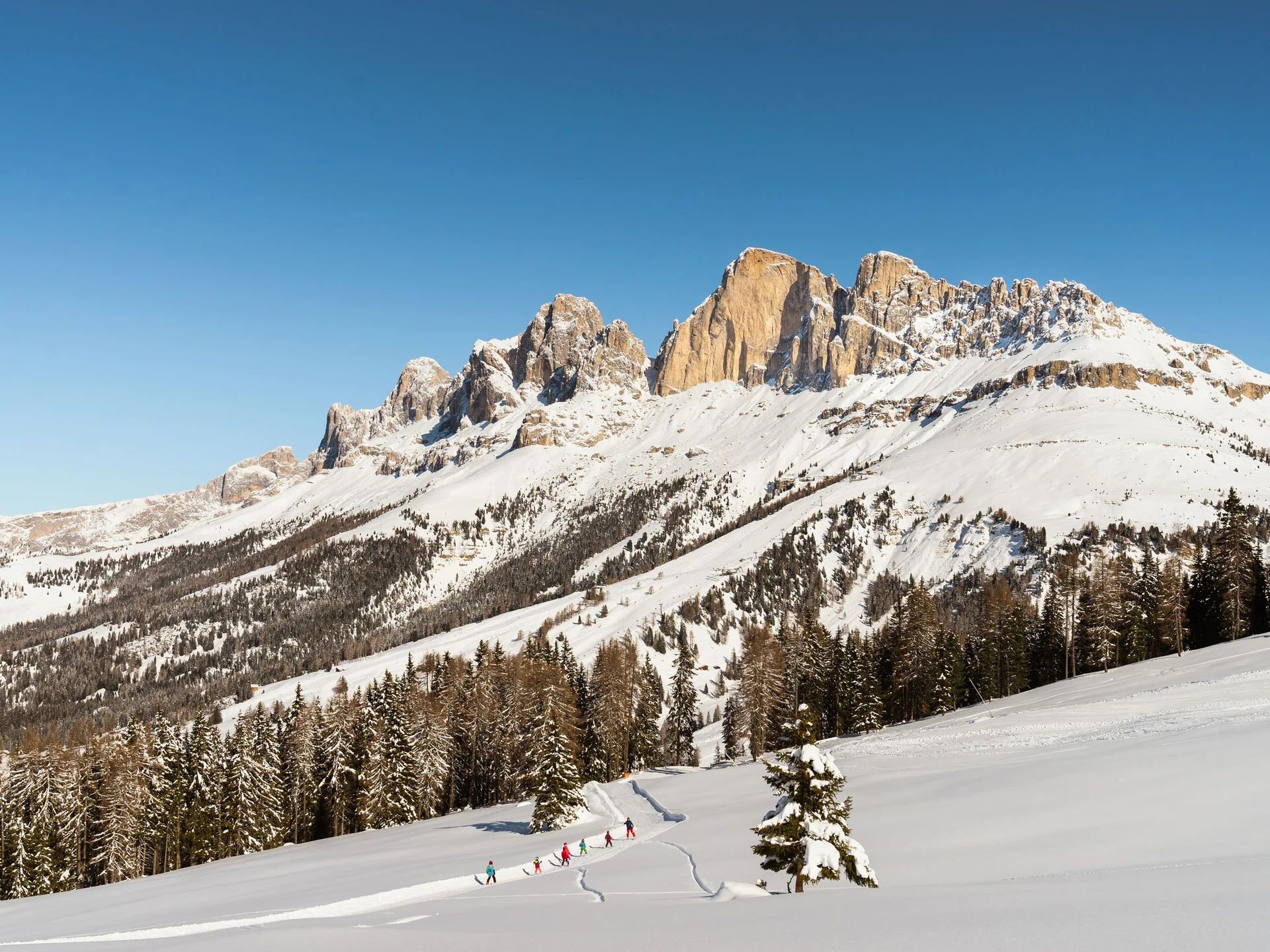 Ihr werdet dieses Skihotel in den Dolomiten lieben. Schnee bedeckte Dolomiten mit Skifahrern auf einer Piste