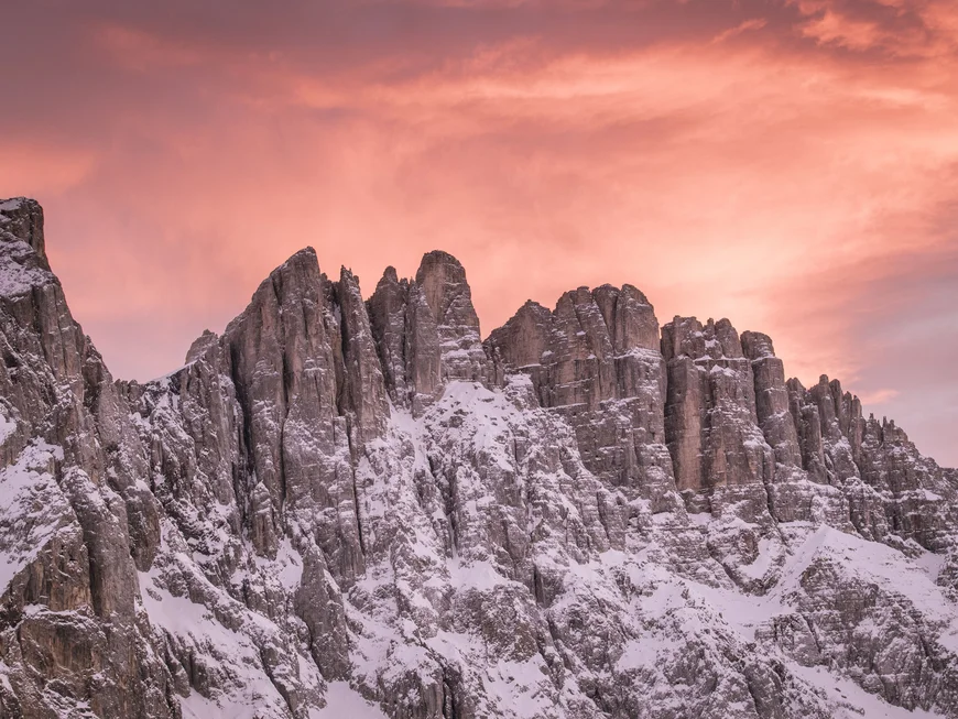 Schneebedeckte Dolomiten bei Sonnenuntergang mit orangefarbenem Himmel