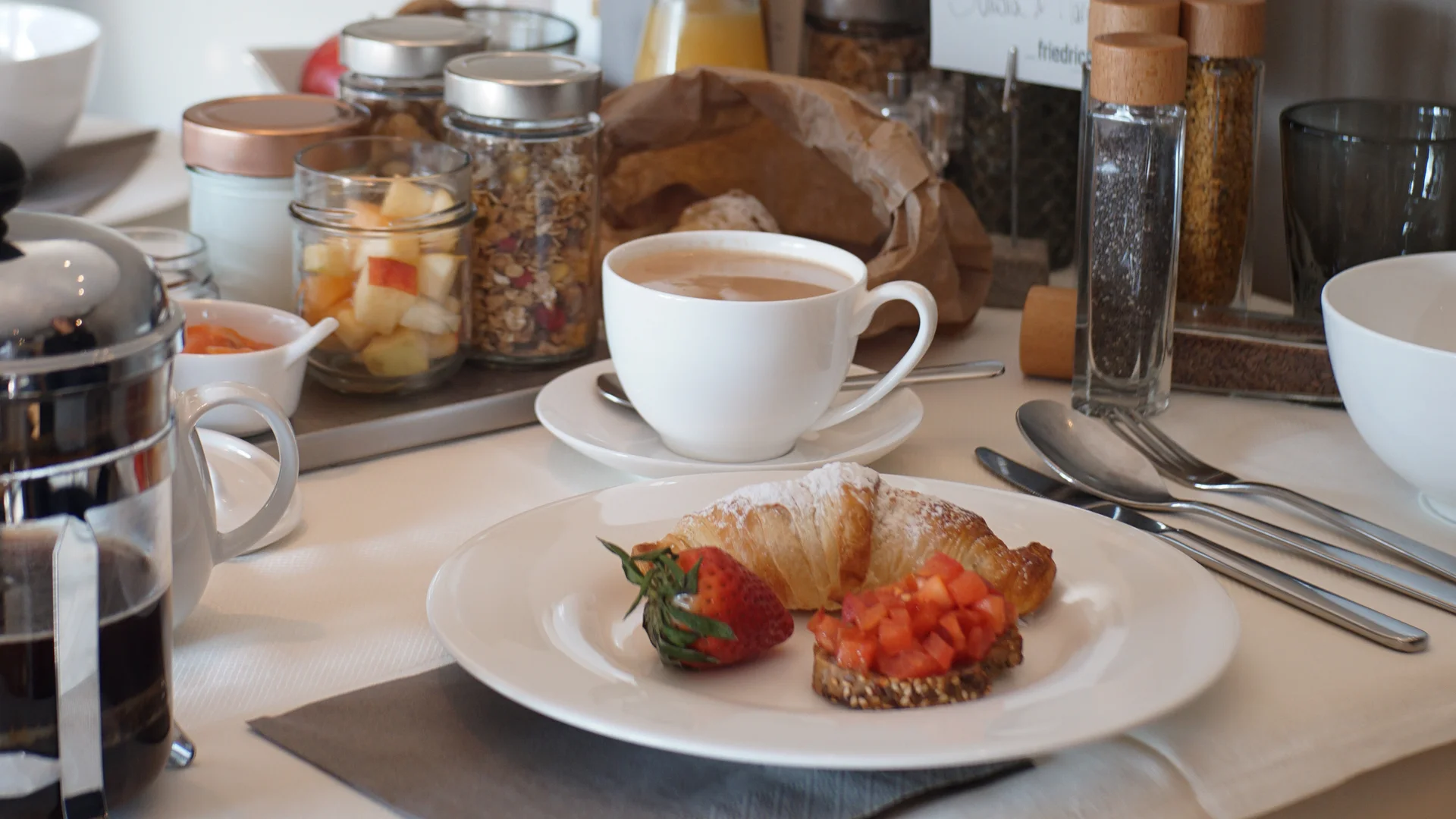 Das Friedrich Frühstück in Südtirol Frühstückstablett mit Croissant, Kaffee, Brot und frischem Obst auf gedecktem Tisch