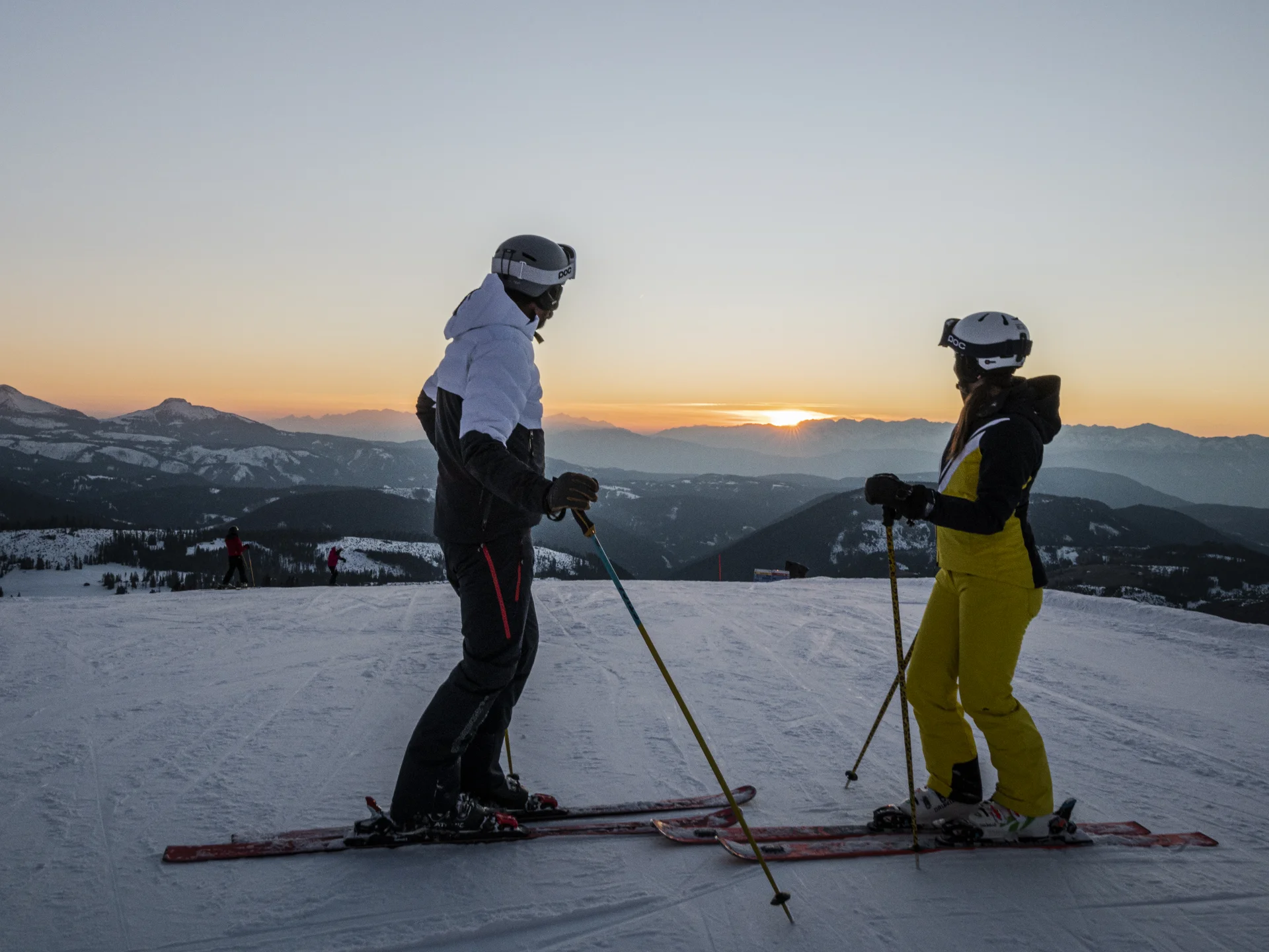Ihr werdet dieses Skihotel in den Dolomiten lieben. Zwei Skifahrer schauen sich beim Sonnenuntergang in den Bergen an