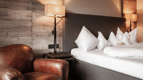 Friedrich ist DAS Boutiquehotel in den Dolomiten Gemütliches Hotelzimmer mit Ledersessel, Nachttischlampen und weißem Bett