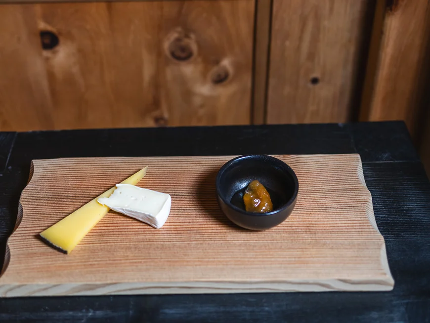 Regionale Küche in Südtirol Holzbrett mit drei Käsesorten und Marmelade vor Holztür mit Metallgriff