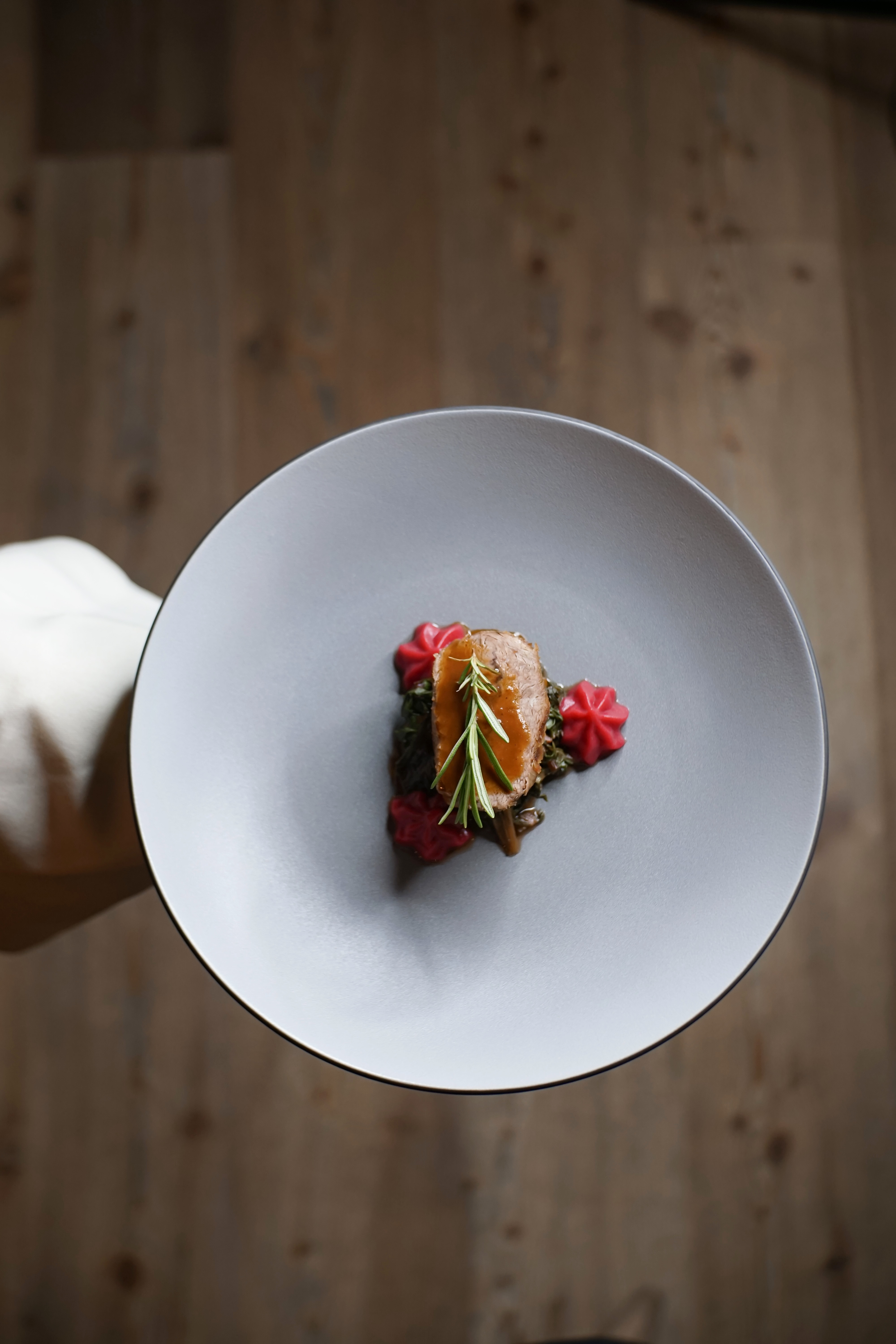 Accessibility Elegant dish with meat, sauce, and rosemary on gray plate